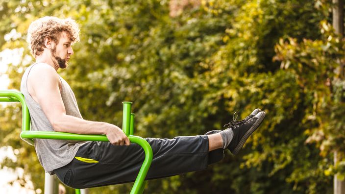 Active man exercising on leg raise outdoor.