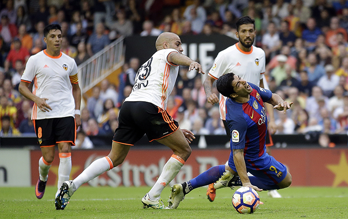 FC Barcelona's Luis Suarez, right, wins a penalty as he is brought down by Valencia's Aymen Abdennour, second left, during the Spanish La Liga soccer match between Valencia and FC Barcelona at the Mestalla stadium in Valencia, Spain, Saturday, Oct. 22, 2016. (AP Photo/Manu Fernandez)