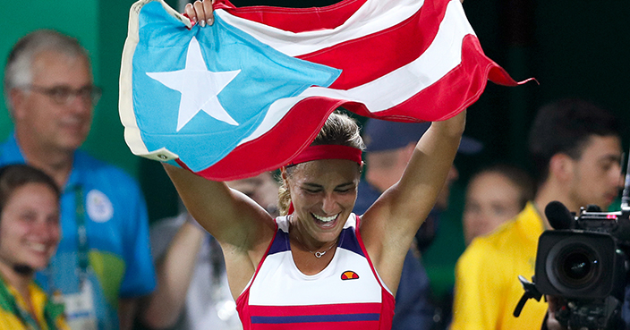 Monica Puig of Puerto Rico celebrates holding her country's flag after winning the gold medal match in the women's tennis competition at the 2016 Summer Olympics in Rio de Janeiro, Brazil, Saturday, Aug. 13, 2016. (AP Photo/Vadim Ghirda)