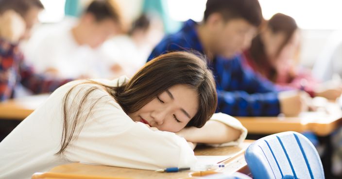 tired and asleep college student  for exam in classroom