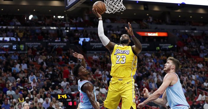 Los Angeles Lakers forward LeBron James (23) shoots over Miami Heat forward Jimmy Butler (22) and forward Meyers Leonard, right, during the first half of an NBA basketball game, Friday, Dec. 13, 2019, in Miami. (AP Photo/Lynne Sladky)